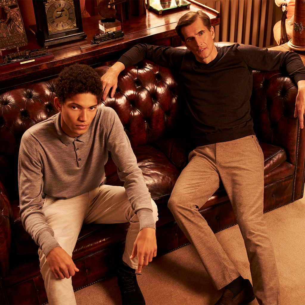 Two men sitting on a leather couch in a room with decorative items.
