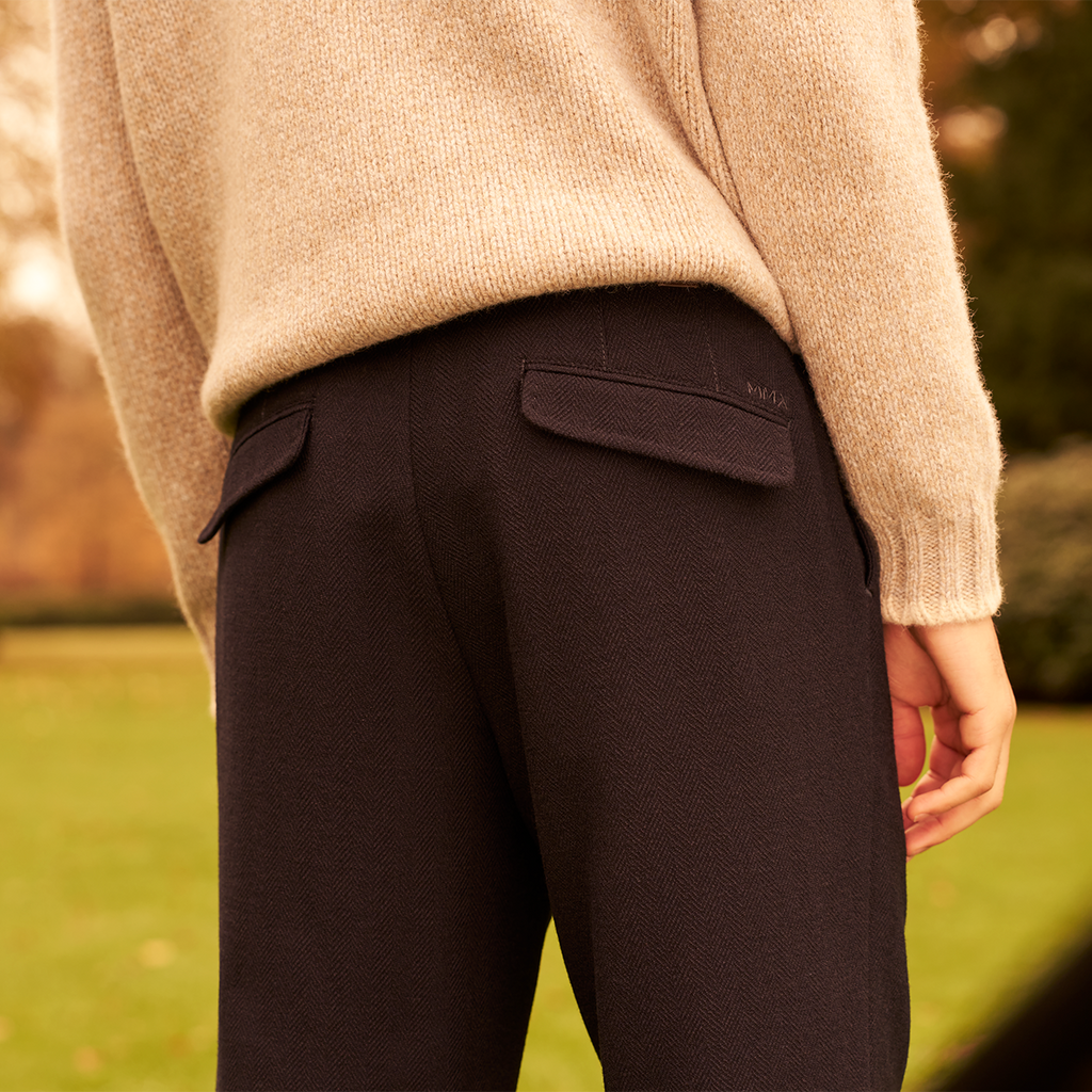 Person wearing dark pants and a beige sweater outdoors