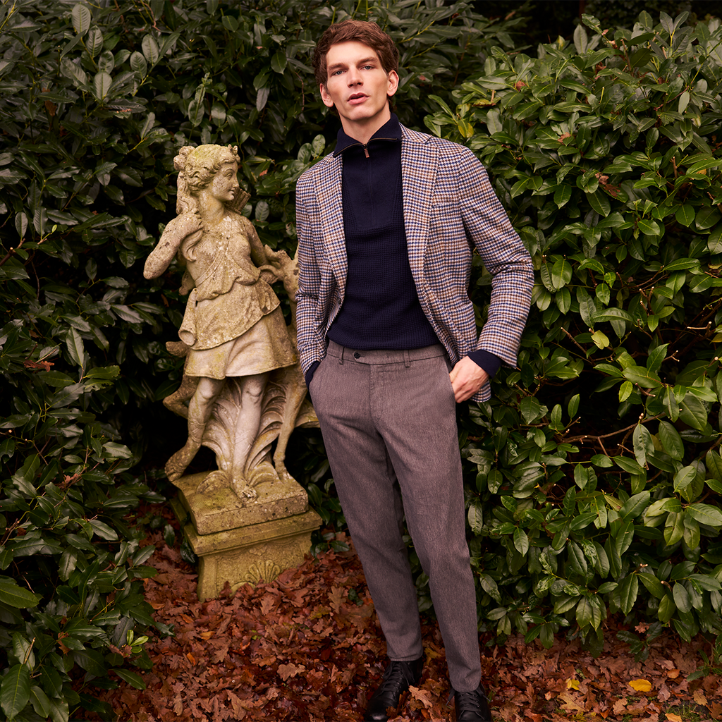 Man standing next to a statue in a garden setting