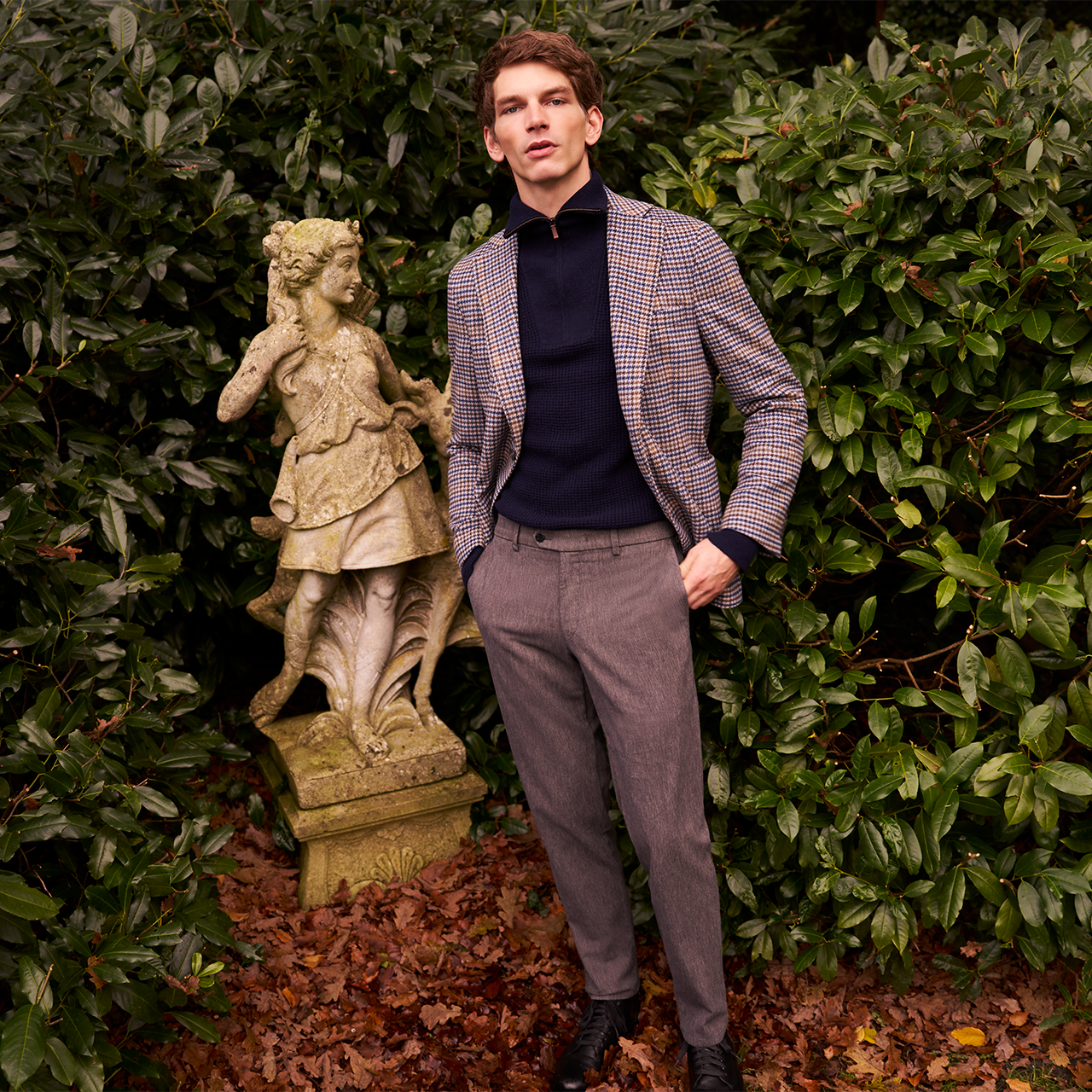 Man standing next to a statue in a garden setting